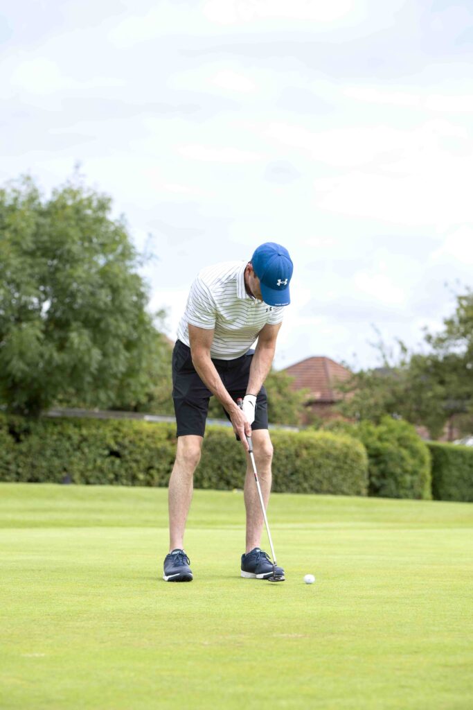 Client Event Day with Cullen Wealth and Cheadle Sports Club at Bramhall Park Golf Course. The image features a gentleman putting a ball to his right-hand side. The man is wearing a white tee, with a light blue cap.